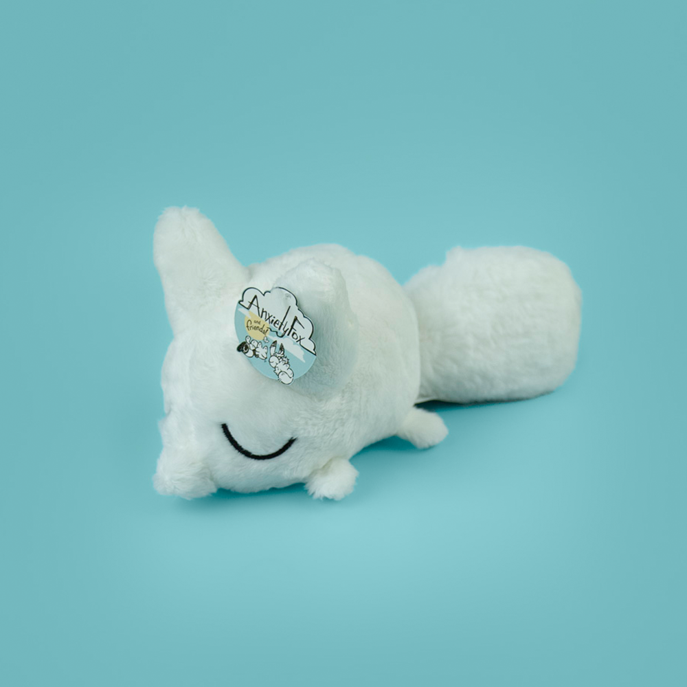 Plush toy of a white fox against a light blue background