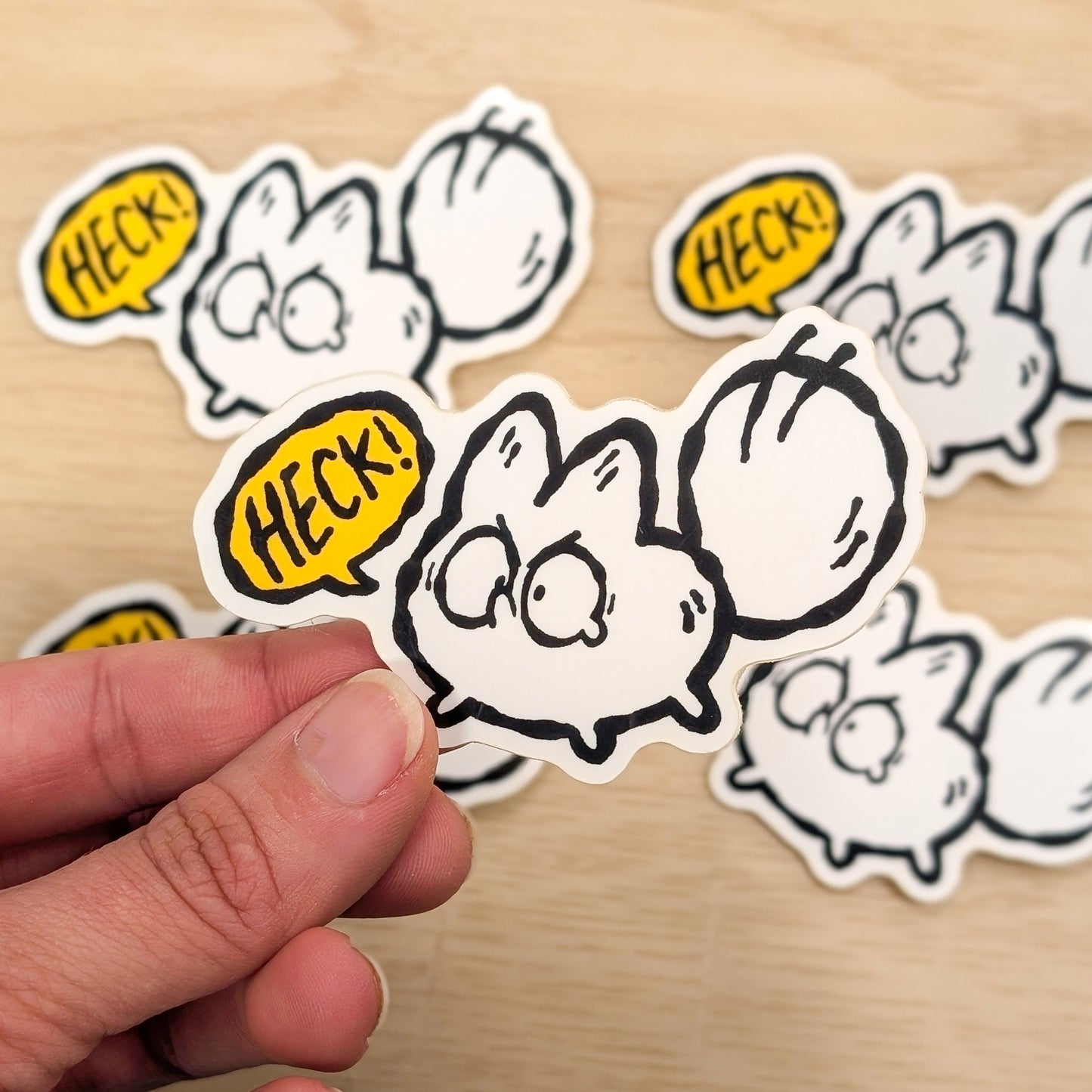 Stickers with cartoon character white fox and 'HECK!' text on a wooden surface