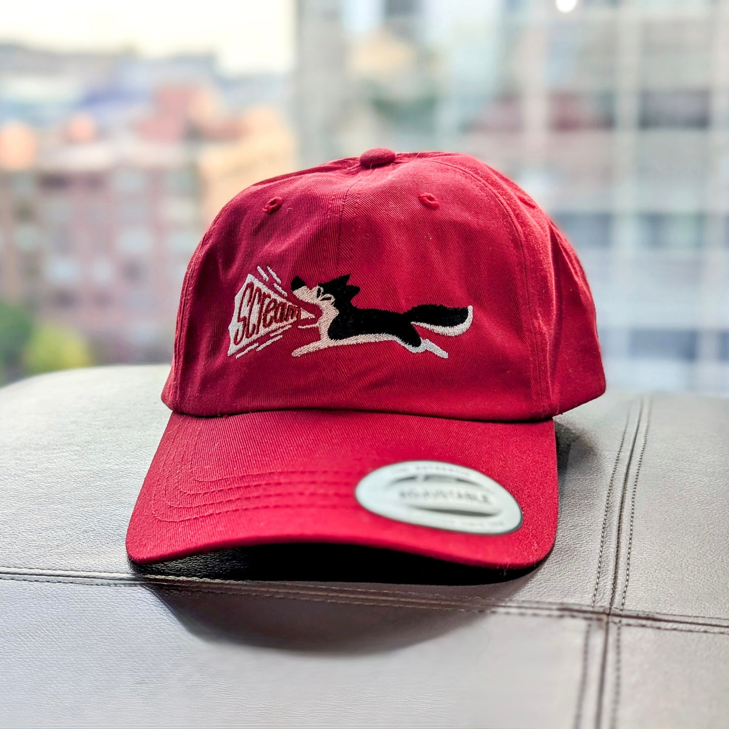 A red snapback hat with an embroidered black and white siberian husky on the front. The husky has its mouth wide open and is screaming!