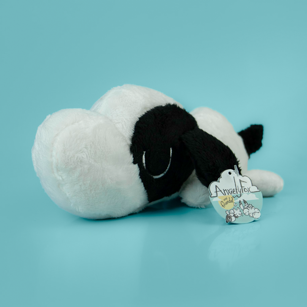 Plush toy of a black and white dog on a light blue background