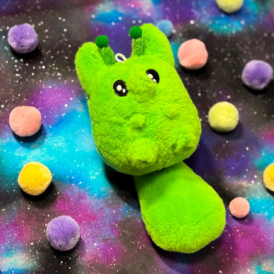 Green alien fox plush toy with a space-themed background featuring colorful planets.