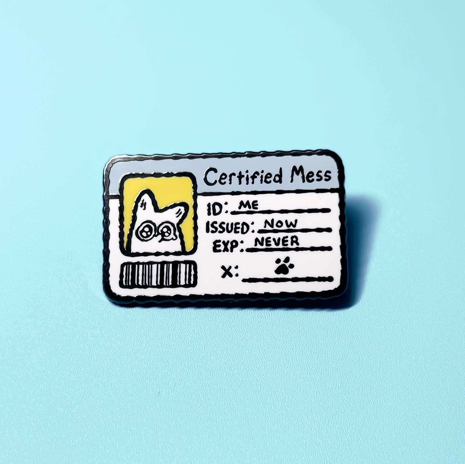 Enamel pin with a design resembling a 'Certified Mess' badge on a light blue background