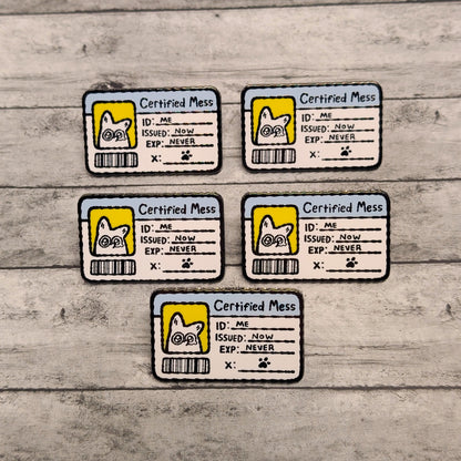 Five 'Certified Mess' enamel pins with cartoon white fox designs on a wooden surface.