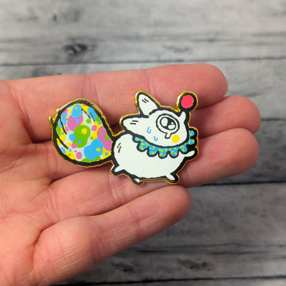 Colorful cartoon-style clown white fox pin held in a hand on a wooden surface