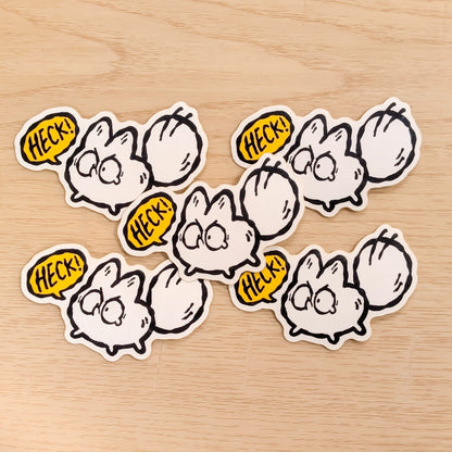 Set of six cartoon-style white fox stickers with speech bubbles saying 'HECK!' on a wooden surface.
