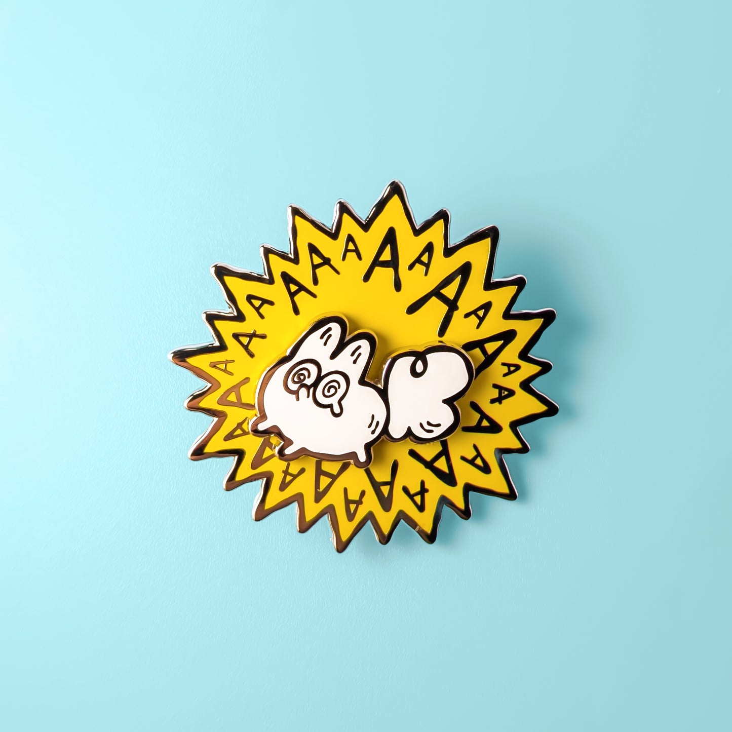 Enamel pin with a cartoon white fox and 'AA' text on a light blue background