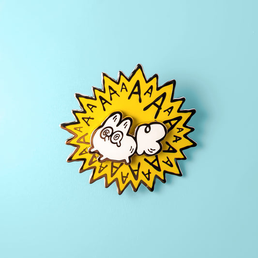 Enamel pin with a cartoon white fox and 'AA' text on a light blue background