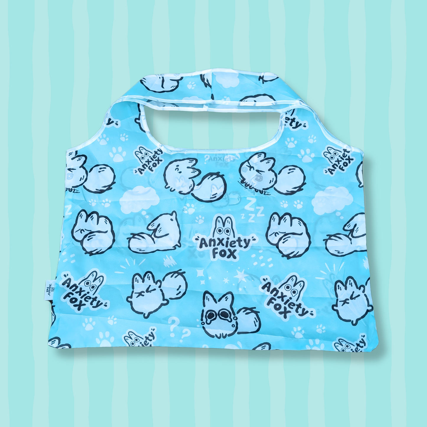 Blue reusable tote bag featuring illustrations of a cartoon white fox