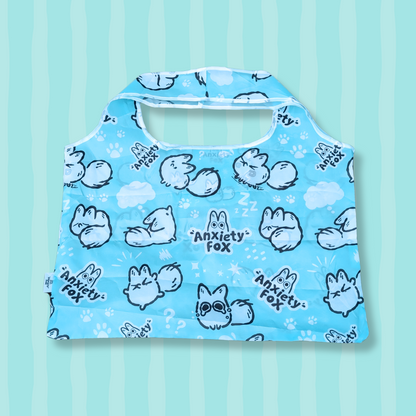 Blue reusable tote bag featuring illustrations of a cartoon white fox