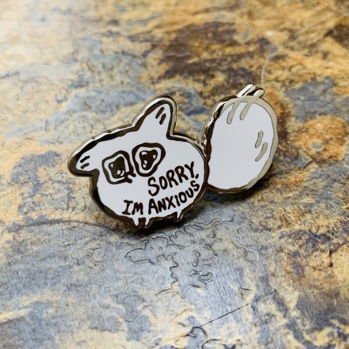 Enamel pin with a white fox design and 'Sorry, I'm Anxious' text on a stone background