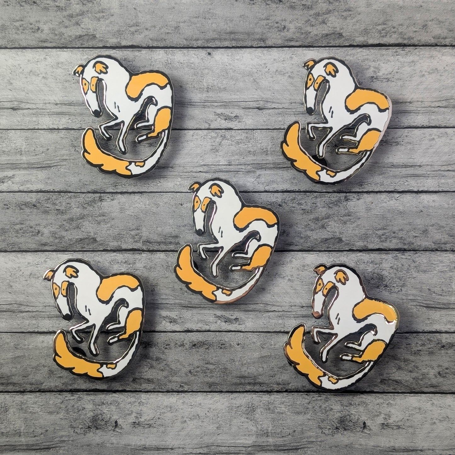 Five Borzoi dog pins with white bodies and orange accents on a wooden surface