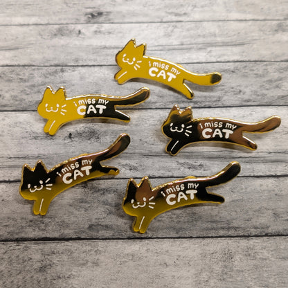 Five cat-shaped pins with 'I miss my CAT' text on a wooden surface