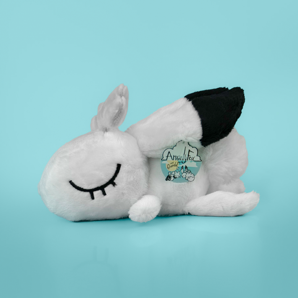 Plush toy of a white rabbit with black accents, against a light blue background