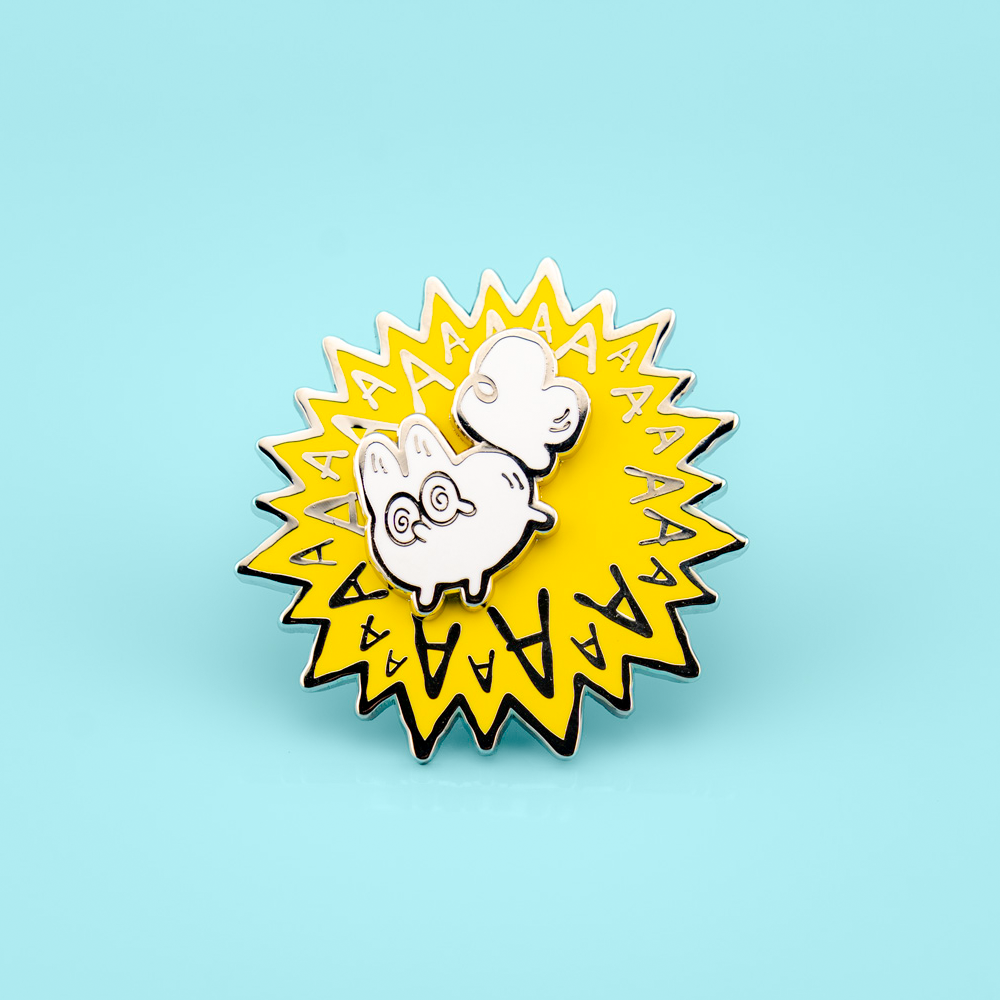 Enamel pin with a cartoon white fox and 'AA' text on a light blue background
