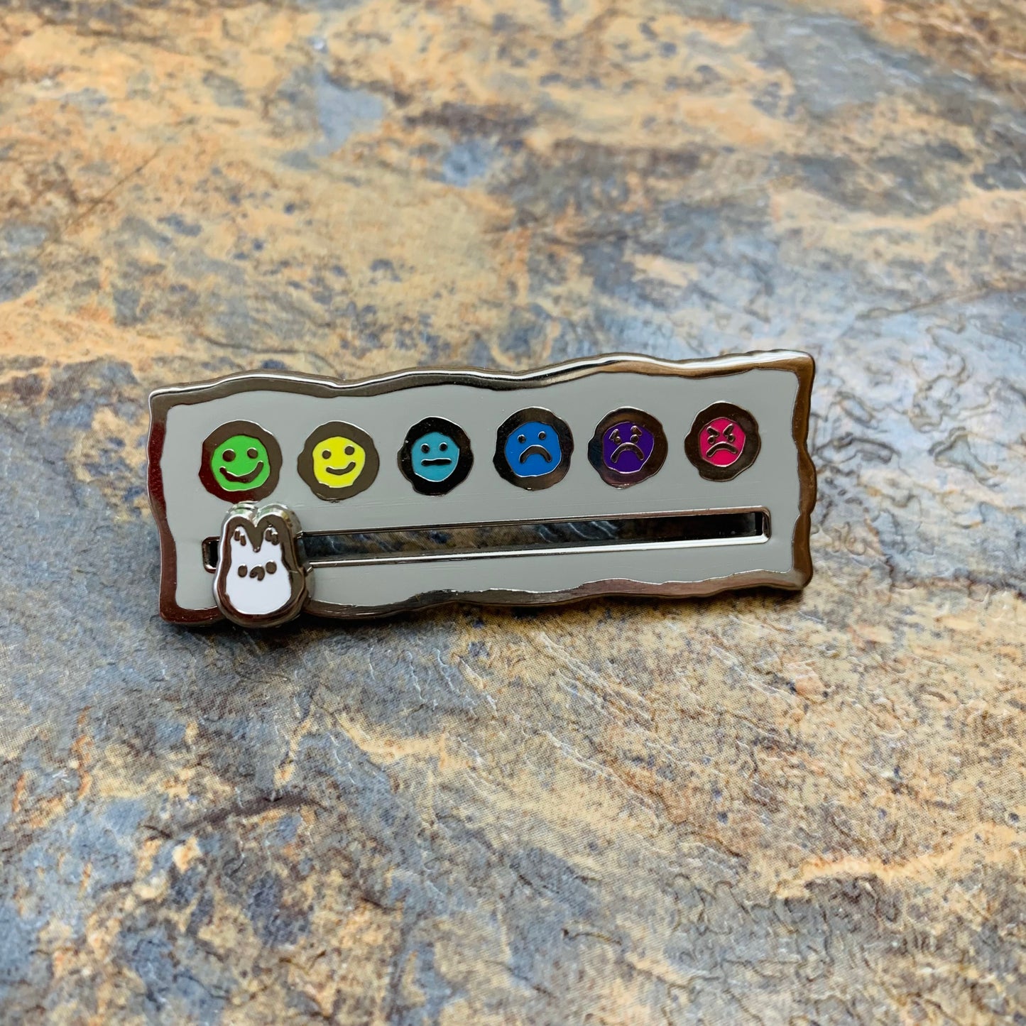 Mood tracker enamel pin on a stone background
