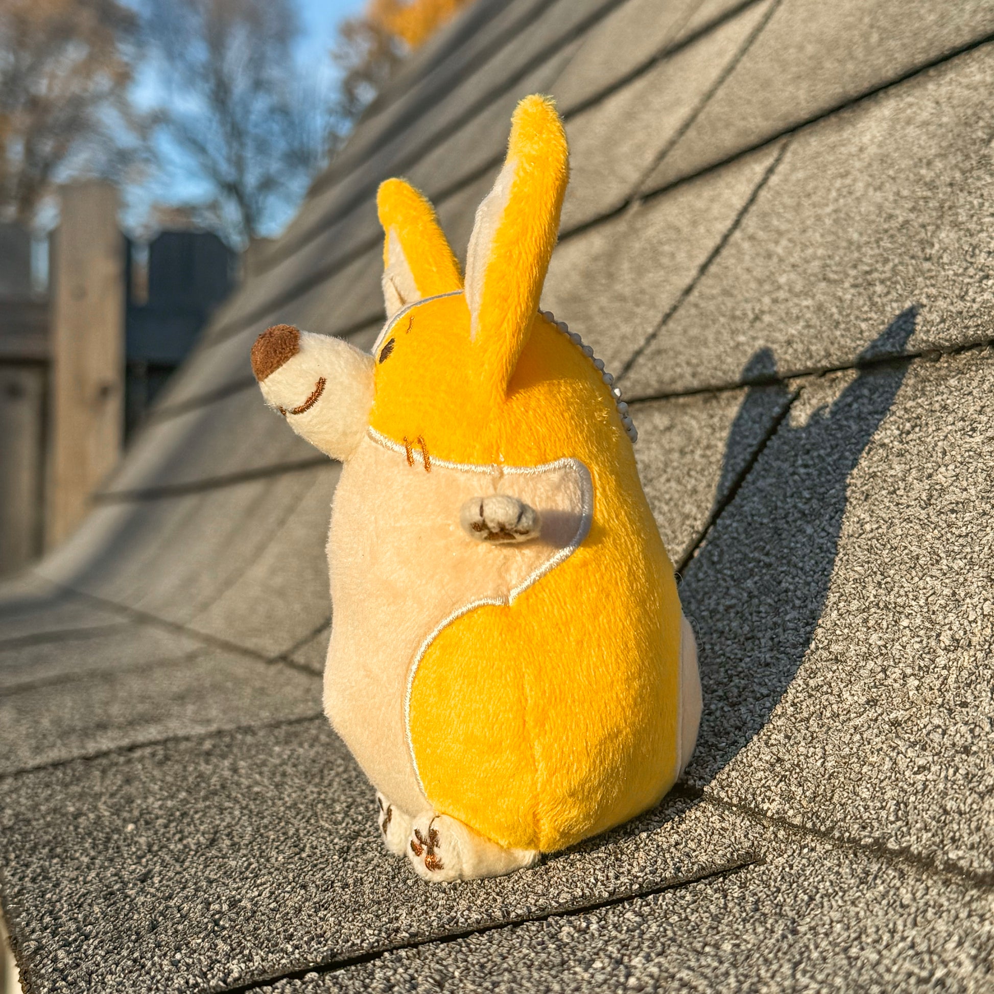 Plush toy of a corgi sitting on the roof of a house