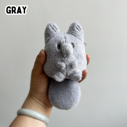 A hand holding a mini gray fox plush toy against a white background
