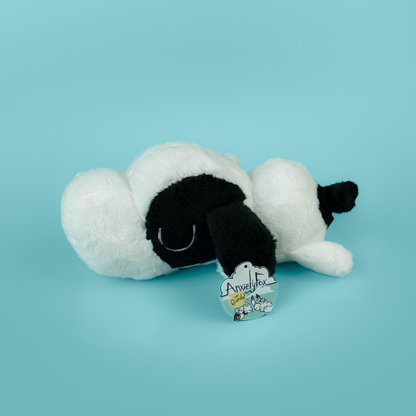 Plush toy of a black and white dog on a light blue background