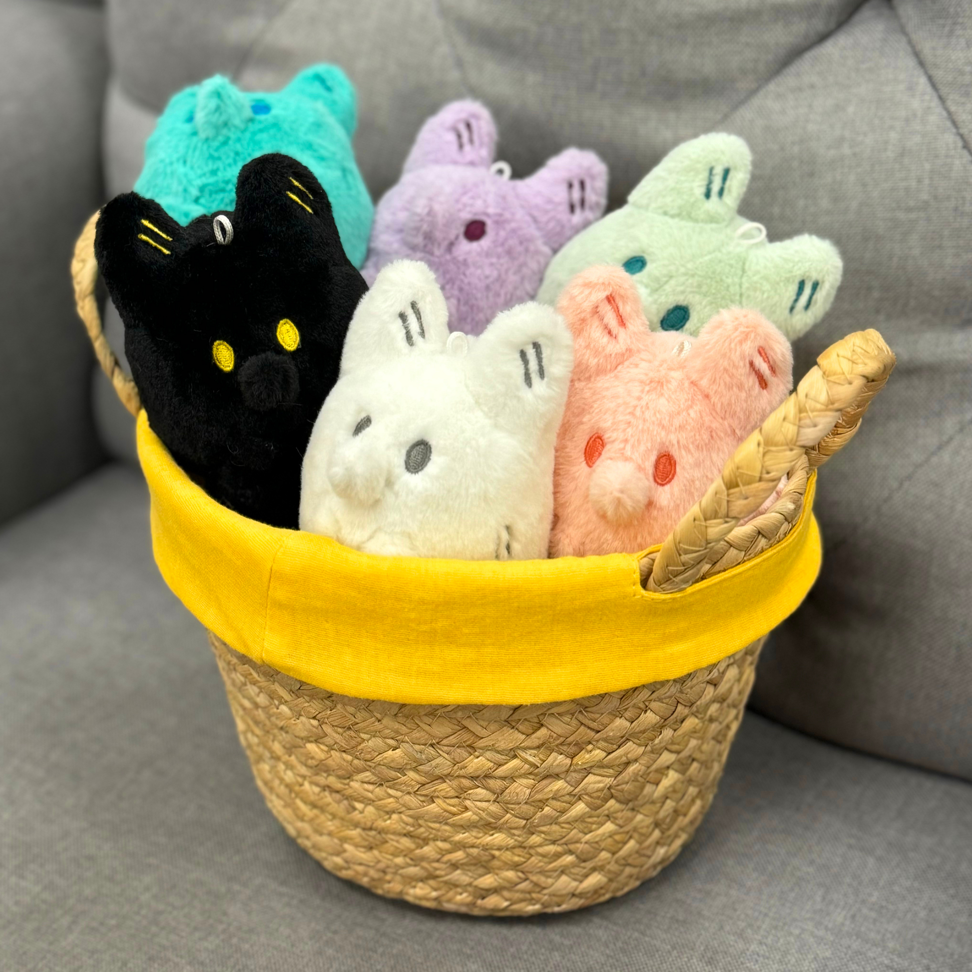White, black, pink, light green, light purple, and teal fox plush toys in a basket.