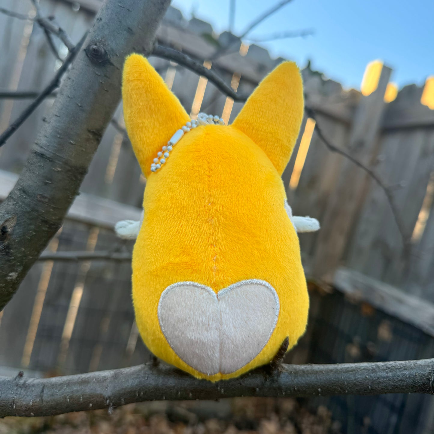 Back view of a plush toy of a corgi with a heart on its bottom