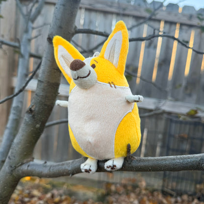 Plush toy of a corgi sitting in a tree