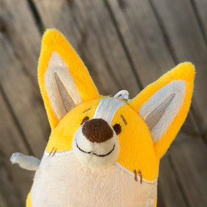 Closeup of a plush toy of a corgi with a wooden background