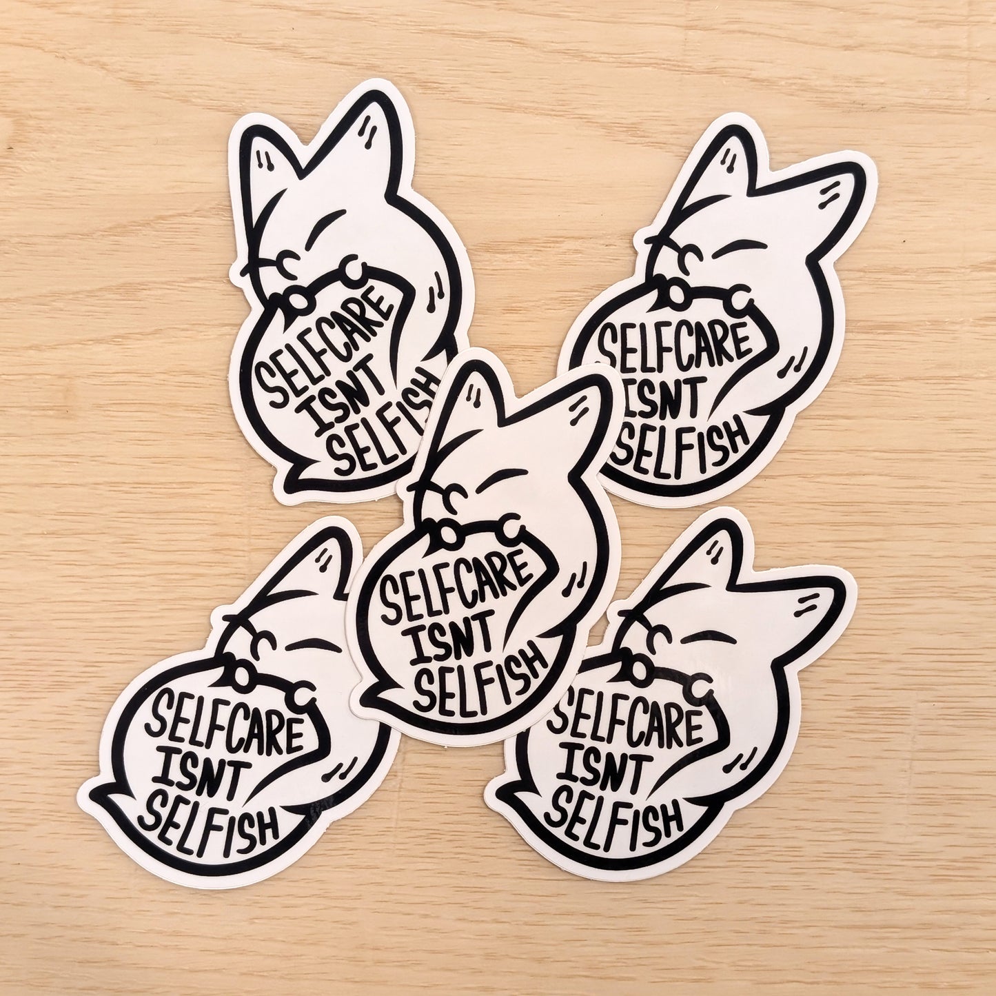 Four fox-shaped stickers with 'Self care isn't selfish' text on a wooden surface