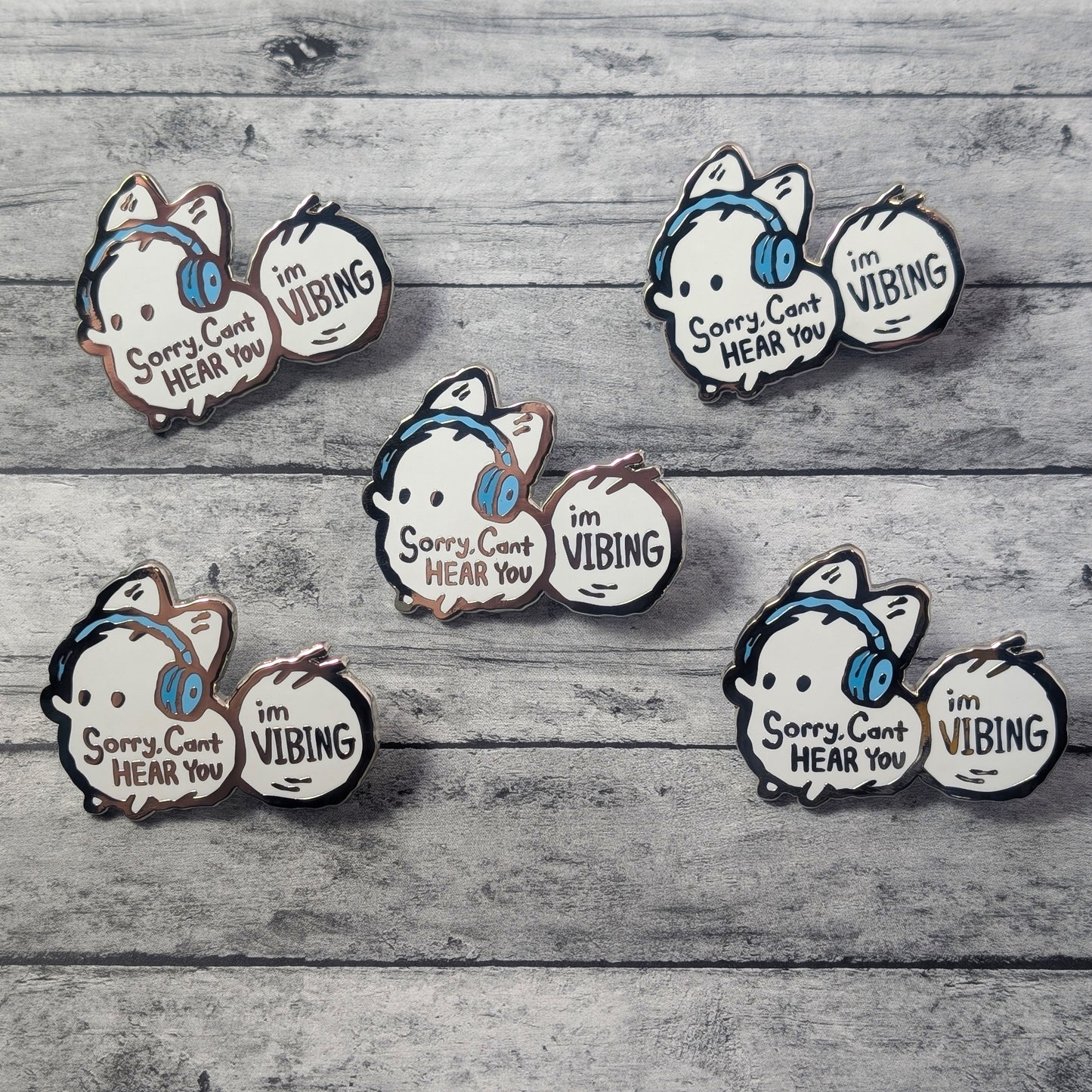 Set of cartoon white fox pins with text on a wooden surface