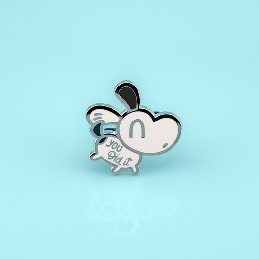 Bright yellow enamel pin featuring a cute puppy with "You Did It!" text, made by Made By Nao! for ADHD awareness and celebration.