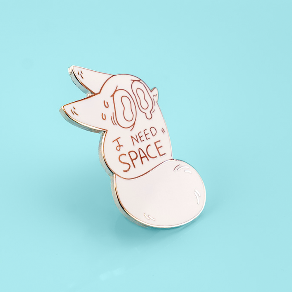 An enamel pin featuring a cute fox with space-themed elements, designed by Made By Nao! for the "I Need Space" anxiety-themed collection.
