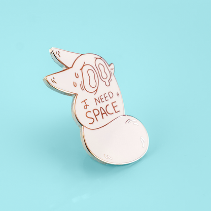 An enamel pin featuring a cute fox with space-themed elements, designed by Made By Nao! for the "I Need Space" anxiety-themed collection.