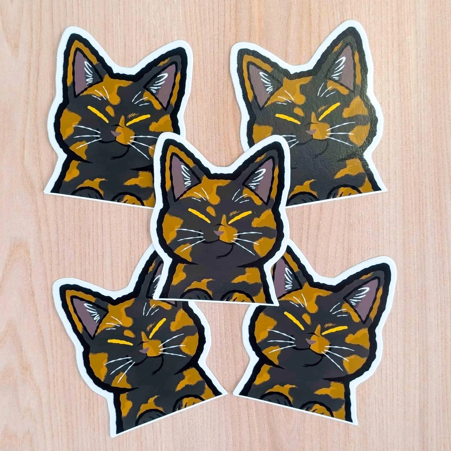 Tortoiseshell cat Peeker vinyl sticker by Made By Nao! featuring a cute feline face with vibrant orange and black colors.