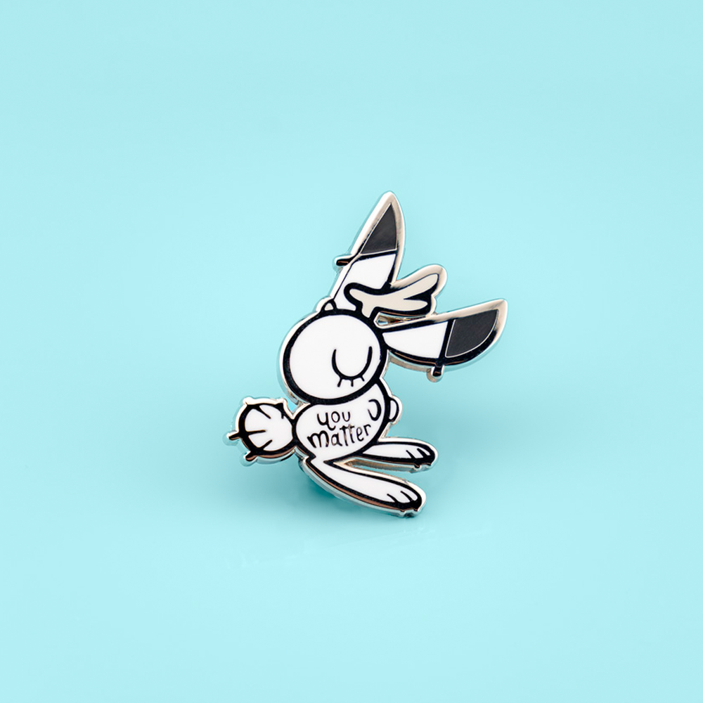 Support bunny enamel pin by Naomi Romero Art featuring a cute bunny design, perfect for expressing positivity and support.