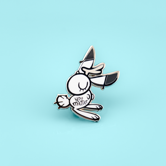 Support bunny enamel pin by Naomi Romero Art featuring a cute bunny design, perfect for expressing positivity and support.